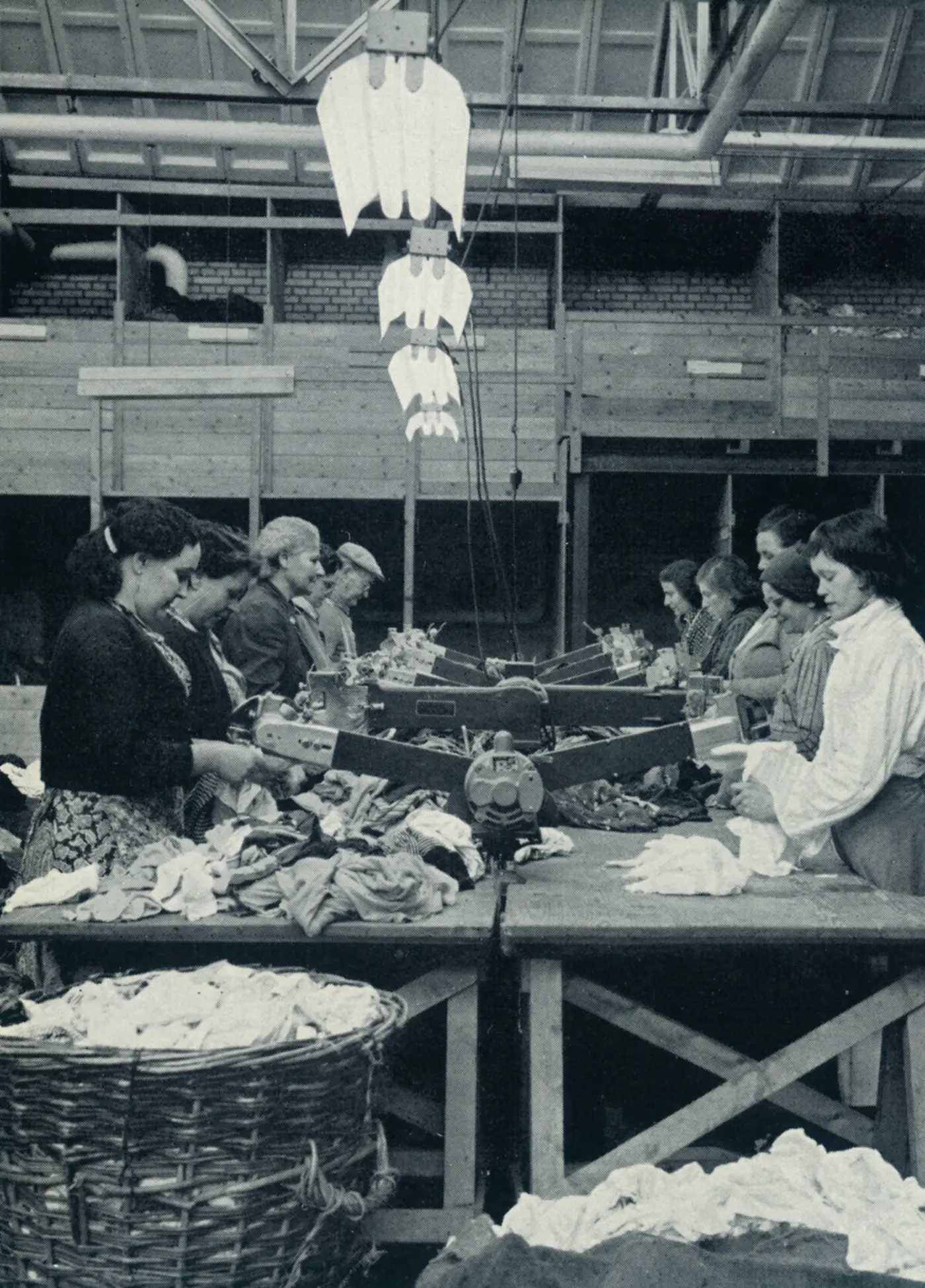 Werkneemsters aan een sorteertafel met een stervormige machine, in de voormalige fabriek