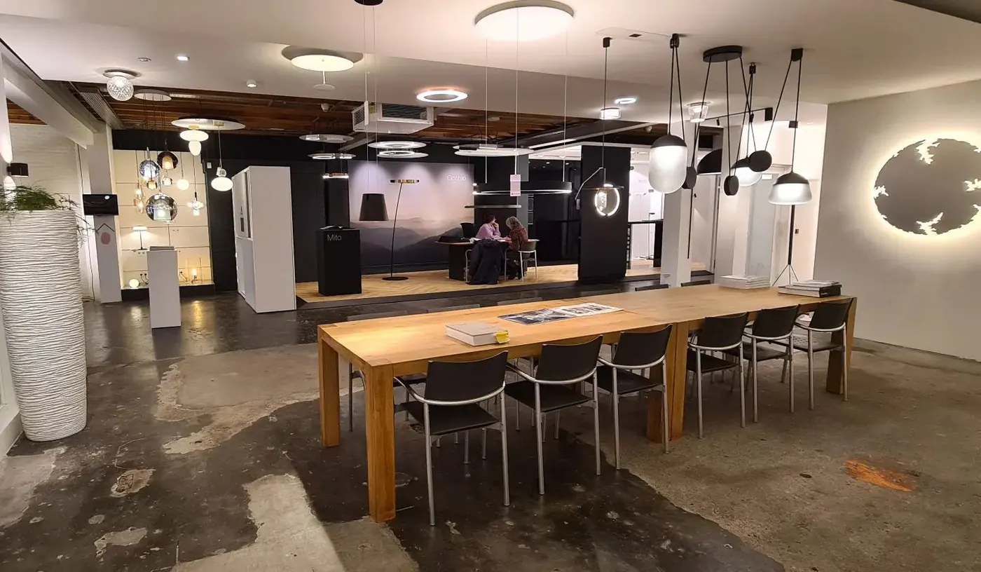 Showroom met tientallen hanglampen in rijen onder een donker plafond
